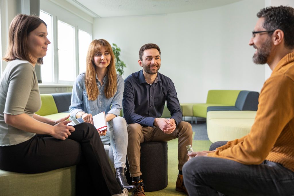 Group of four EOS colleagues sitting in workshop area and discuss a topic