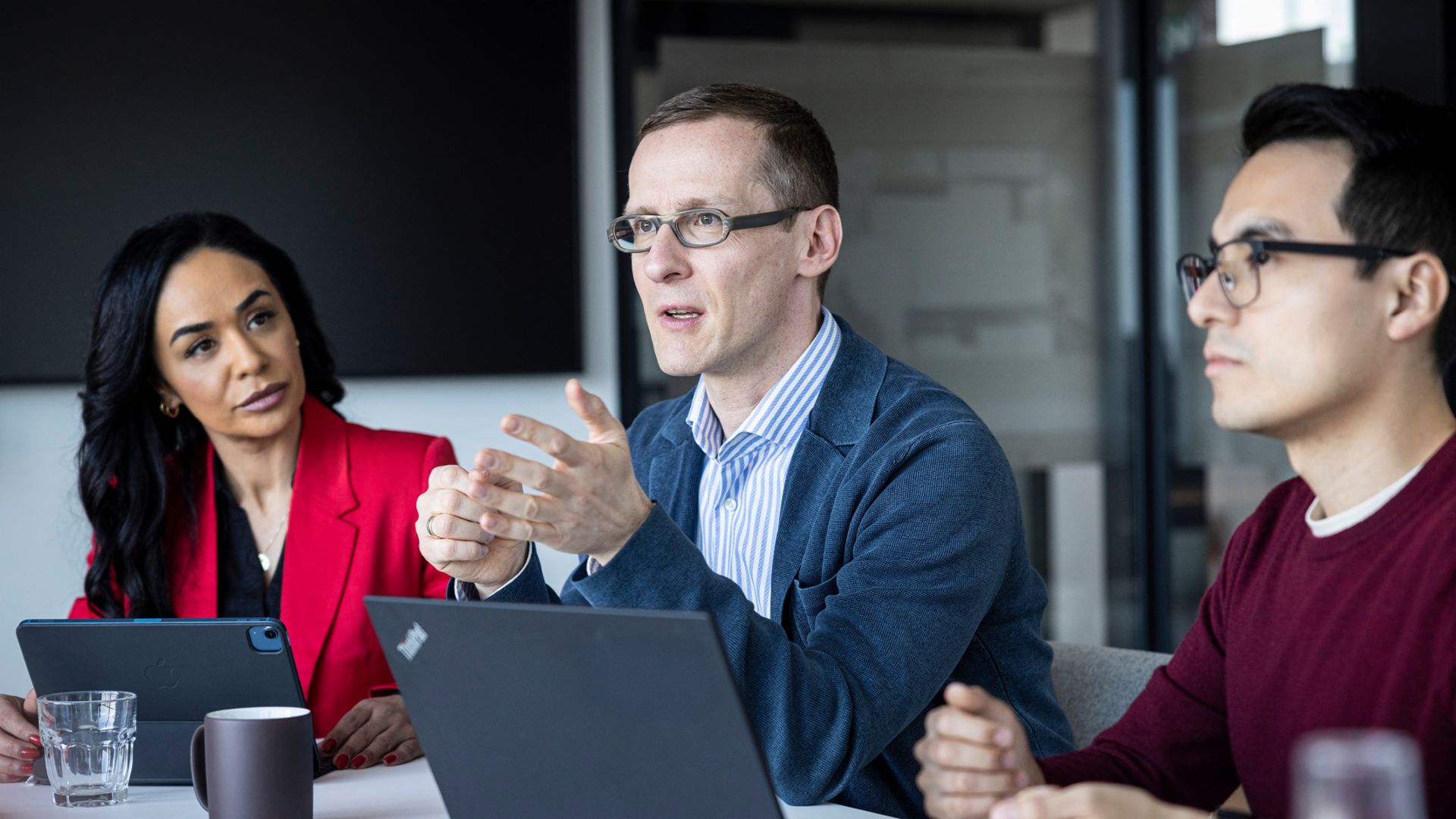 Három személy beszélget egy irodában.